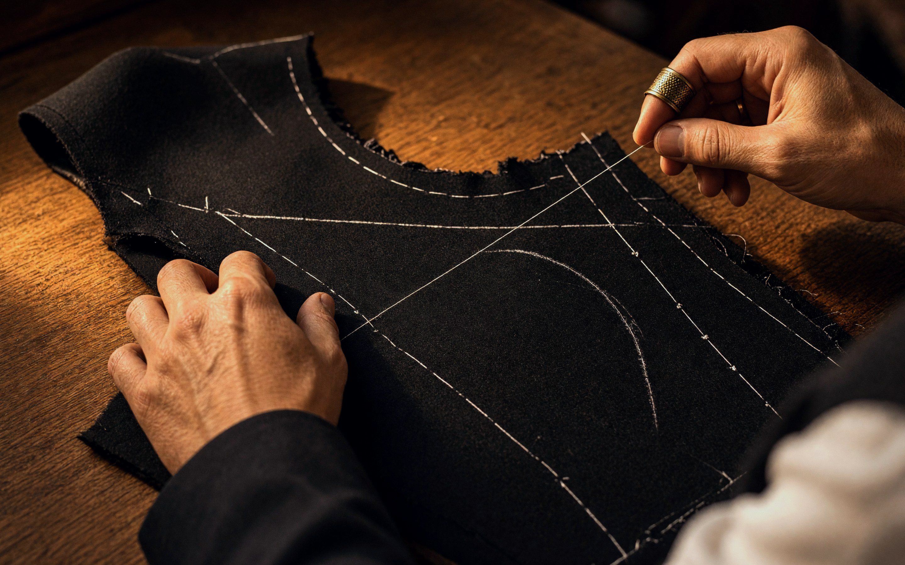 A Hajjo tailor basting the cut panels of a navy jacket
